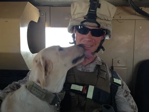 Lee in uniform in Afghanistan with a military working dog